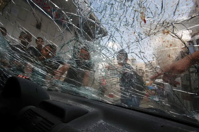 Palestinians look at blood-stains on the windscreen of a damaged car belonging to a Palestinian man was killed by Israeli security forces after he attempted to ram his vehicle into Israeli border guards in the Shufat refugee camp, in east Jerusalem, early in the morning on September 5, 2016. (Photo by Hazem Bader/AFP Photo)