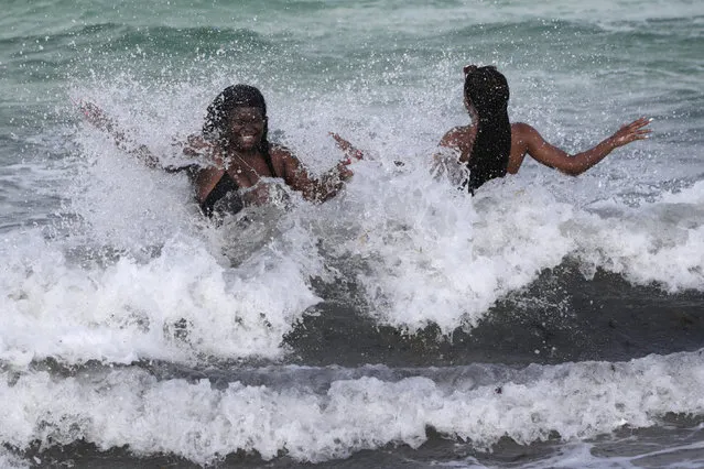 Women enjoy the waves from a high surf, Friday, July 31, 2020, in Miami Beach, Fla. Forecasters declared a hurricane warning for parts of the Florida coast Friday as Hurricane Isaias drenched the Bahamas on track for the U.S. East Coast. (Photo by Lynne Sladky/AP Photo)