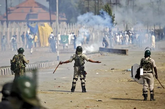 An Indian policeman gestures towards Kashmiri demonstrators during a protest after Eid al-Adha prayers in Srinagar, September 25, 2015. Hundreds of demonstrators on Friday protested against a beef ban order by a state court in India's Kashmir, local media reported. (Photo by Danish Ismail/Reuters)