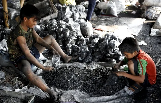 Boys work at a charcoal repacking shop used for cooking at Las Pinas, Metro Manila October 6, 2015. (Photo by Erik De Castro/Reuters)
