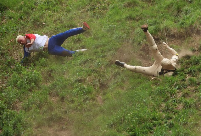Contestants in the men's downhill race chase the cheese down the hill during Gloucestershire's famous Cheese-Rolling contest on May 26, 2025 in Brockworth, England. Every year competitors and spectators from around the world gather for the Cooper's Hill Cheese-Rolling competition that sees participants fling themselves down a steep hill in pursuit of a rolling 7 pound (3 kilogram) wheel of Double Gloucester cheese. The first contestant to the bottom of the 590 foot (180 meter) Cooper's Hill wins the wheel of cheese. The ankle-breaking extreme sport has officially been recorded since 1826, but is thought to have roots in an ancient pagan tradition. (Photo by Cameron Smith/Getty Images)