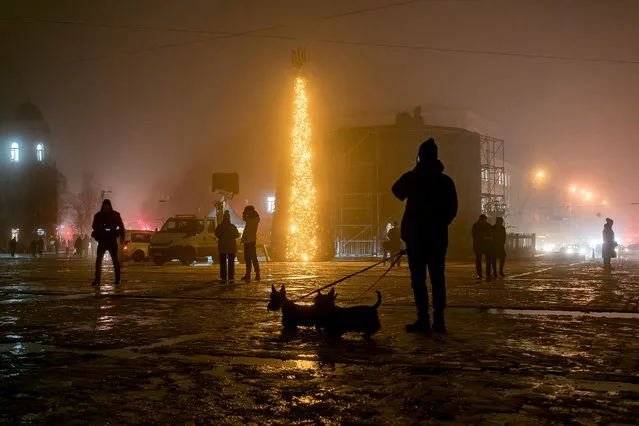 People walk past a Christmas tree during heavy fog at the Sofiyska square, amid Russia's invasion of Ukraine, in Kyiv, Ukraine on December 17, 2022. (Photo by Vladyslav Musiienko/Reuters)