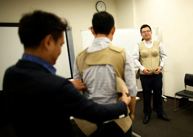Participants try to wear 7-kilogram pregnancy jackets as they take part in an “Ikumen” course, or child-rearing course for men, organized by Osaka-based company Ikumen University, in Tokyo, Japan September 18, 2016. (Photo by Issei Kato/Reuters)