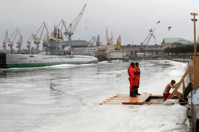 A man (R) bathes in the Neva River through a hole on its frozen surface on the occasion of the Orthodox Epiphany in Saint Petersburg, Russia, 19 January 2023. People believe that bathing in the blessed waters during the feast of the Epiphany strengthens their spirit and body. (Photo by Anatoly Maltsev/EPA/EFE/Rex Features/Shutterstock)