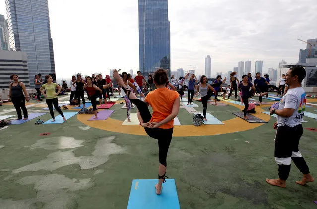 People take part in a sunrise yoga class on the helicopter landing pad on the roof of the Grand Sahid Jaya hotel in Jakarta, Indonesia September 25, 2016. (Photo by Darren Whiteside/Reuters)
