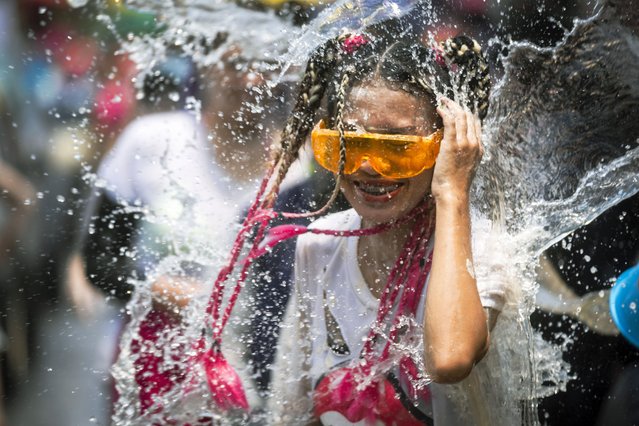 A bucket of water is splashed on a woman during the Songkran water festival to celebrate the Thai New Year, in Prachinburi Province, Thailand, April 13, 2024. (Photo by Wason Wanichakorn/AP Photo)