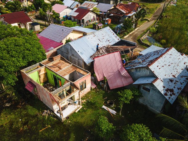 This aerial picture show people checking damage to the roof of a house after monsoon rains in Pekan Bada, Aceh province on July 21, 2025. (Photo by Chaideer Mahyuddin/AFP Photo)