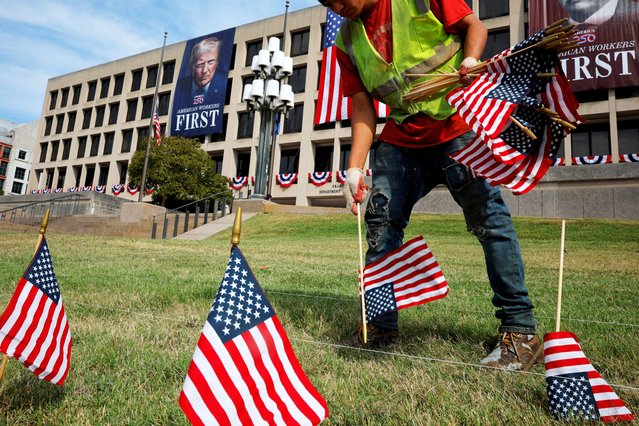A worker plants U.S. flags in front of the Department of Labor building, displaying banners depicting President Trump, in Washington, on August 28, 2025. (Photo by Brian Snyder/Reuters)