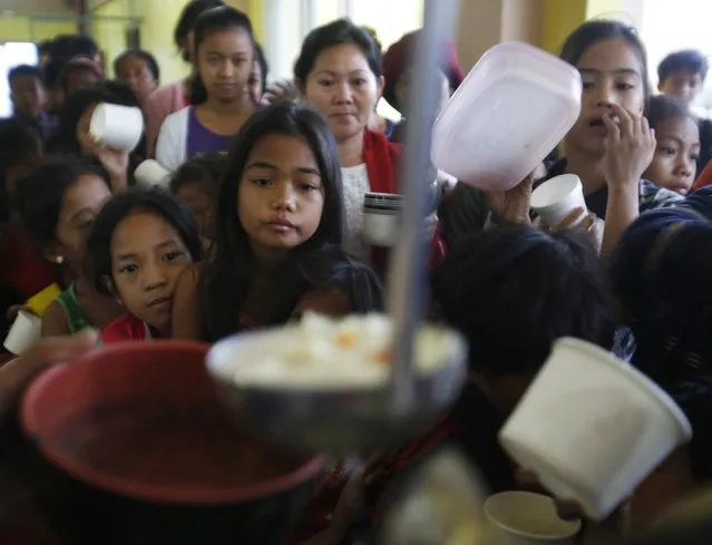 People queue for food at an evacuation centre for the coastal community, to shelter from typhoon Hagupit, near Manila, December 8, 2014. Hundreds of thousands of Filipinos began to return to their homes battered by a powerful typhoon at the weekend, but the nation collectively breathed a sigh of relief as a massive evacuation plan appeared to minimise fatalities. (Photo by Cheryl Gagalac/Reuters)
