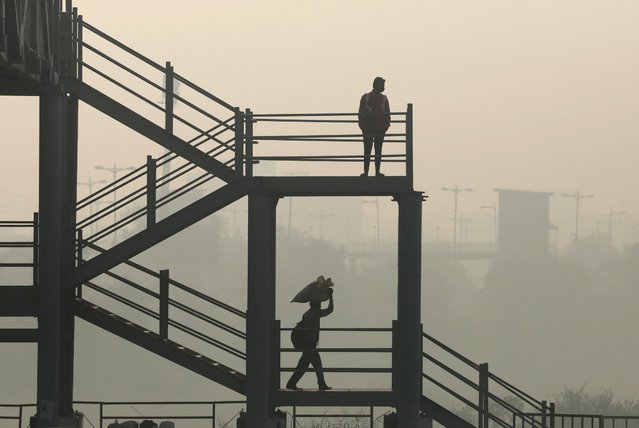 Men are seen on a skywalk near Delhi-Meerut Expressway on a smoggy day in New Delhi, India, October 30, 2020. (Photo by Anushree Fadnavis/Reuters)