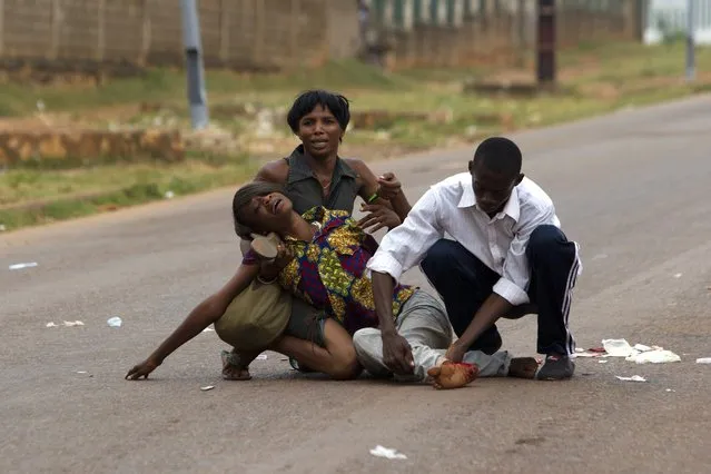 A woman is assisted after she was injured by a tear gas canister shot by African Union (AU) soldiers to disperse a crowd near the district of Miskine in the capital Bangui, in this February 7, 2014 file photo. (Photo by Siegfried Modola/Reuters)