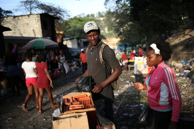 A man selling hot-dogs speaks to a customer in Port-au-Prince, March 15, 2018. (Photo by Andres Martinez Casares/Reuters)