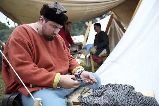 A re-enactor mends his chain mail before a re-enactment of the Battle of Hastings, commemorating the 950th anniversary of the battle, in Battle, Britain October 15, 2016. (Photo by Neil Hall/Reuters)