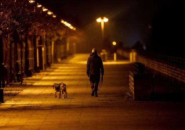A man walks his dog in the outskirts of Frankfurt, Germany, Wednesday, December 16, 2020, the first day of a nationwide lockdown. Germany has entered a harder lockdown, closing shops and schools in an effort to bring down stubbornly high new cases of the coronavirus. (Photo by Michael Probst/AP Photo)