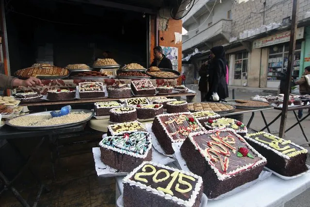 New Year cakes are displayed outside a shop in Sheikh Maksoud neighbourhood of Aleppo December 31, 2014. (Photo by Abdalrhman Ismail/Reuters)
