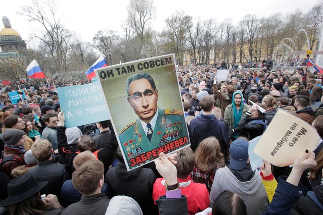 Demonstrators carry a poster depicting Russian President Vladimir Putin as the elderly Soviet Communists party leader Leonid Brezhnev, during a massive protest rally in St.Petersburg, Russia, Saturday, May 5, 2018. Alexei Navalny, anti-corruption campaigner and Putin's most prominent critic, called for nationwide protests on Saturday, two days ahead of the inauguration of Vladimir Putin for a fourth term as Russian president. (Photo by Dmitri Lovetsky/AP Photo)