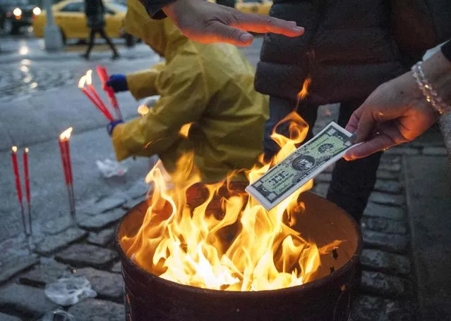 Buddhist mourners burn fake money during a candlelight vigil for slain New York Police Department (NYPD) officer Wenjian Liu one day ahead of his funeral in Manhattan, New York January 3, 2015. Liu, 32, and his partner Rafael Ramos, 40, were shot to death on December 20, 2014 as they sat in their squad car in Brooklyn. (Photo by Stephanie Keith/Reuters)