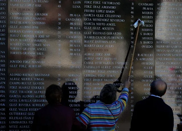 A woman cleans a name on the wall of a memorial grave for Republicans killed during and after the 1936-1939 Spanish civil war at cemetery of San Salvador on the eve of All Saints' Day in Oviedo, northern Spain, October 31, 2016. (Photo by Eloy Alonso/Reuters)