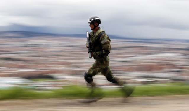 A solider runs to his position to secure a road in the outskirts of Bogota, Colombia, as part of pre-electoral security, Saturday, May 26, 2018. Colombians go to the polls tomorrow to elect a new president. (Photo by Fernando Vergara/AP Photo)