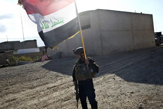 An Iraqi special forces soldier holds up the country's flag in Gogjali, an eastern district of Mosul, Iraq, Wednesday, November 2, 2016. (Photo by Marko Drobnjakovic/AP Photo)
