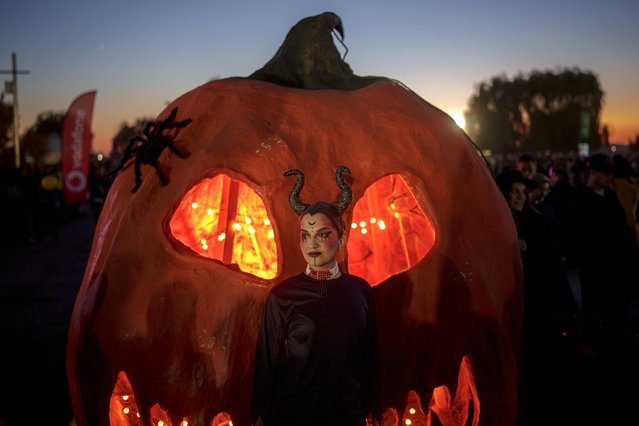 A girl wearing a costume poses next to Hallowwen decorations at the West Side Hallo Fest, a Halloween festival in Bucharest, Romania, Saturday, October 26, 2024. (Photo by Andreea Alexandru/AP Photo)