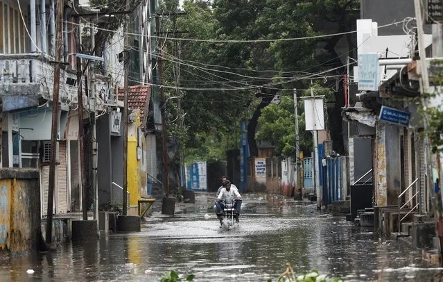 A man rides a motorcycle through a waterlogged street in Mandvi before the arrival of cyclone Biparjoy in the western state of Gujarat, India on June 15, 2023. (Photo by Francis Mascarenhas/Reuters)