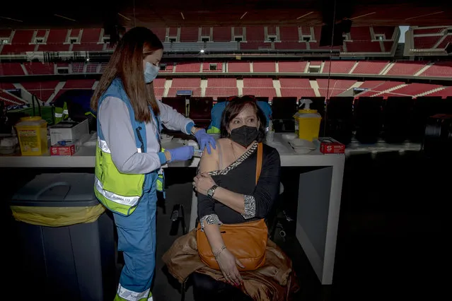 A woman receives a dose of the AstraZeneca vaccine, during a mass vaccination campaign at Wanda Metropolitano stadium in Madrid, Spain, Wednesday, March 24, 2021. Spain resumed the use of the AstraZeneca vaccine on Wednesday by extending it to adults up to 65 years old. (Photo by Manu Fernandez/AP Photo)