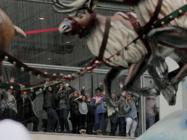 Spectators watching from an office building window wave as Santa Claus passes along Sixth Avenue during the Macy's Thanksgiving Day parade, Thursday, November 24, 2016, in New York. (Photo by Julie Jacobson/AP Photo)