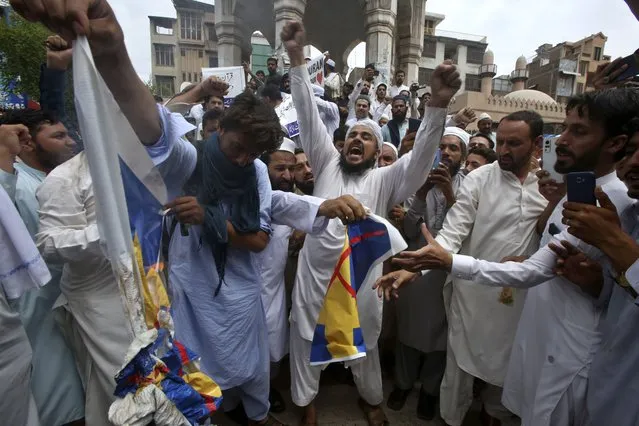 Muslim protestors chant slogans as others burn the representation of Swedish flag during a rally to denounce burning of Islam's holy book “Quran”, in Peshawar, Pakistan, Friday, July 7, 2023. Muslims rallied in across Pakistan to observe a “Day of the Sanctity of Quran” after the South Asian Islamic nation's prime minister issued a call for anti-Sweden protests over last week's burning of Islamic holy book 'Quran' in Stockholm. (Photo by Muhammad Sajjad/AP Photo)