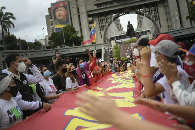 People shout as they hold a sign with a message that reads in Spanish: “Stay strong Colombia”, on Bolivar Avenue in Caracas, Venezuela, Saturday, May 8, 2021, during a gathering of Venezuela government supporters to show solidarity with the protesters in Colombia who were against a proposed tax plan, since withdrawn by the president. (Photo by Matias Delacroix/AP Photo)