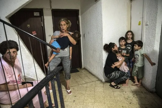 Israelis take shelter in the stairwell of their apartment building as a siren sounds a warning of incoming rockets fired from the Gaza Strip, In Ashdod, Israel, Thursday, May 20, 2021. (Photo by Heidi Levine/AP Photo)