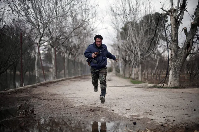 A fighter from Jaish al-Islam (Islam Army), the foremost rebel group in Damascus province who fiercely oppose to both the regime and the Islamic State group, runs in Harasta Qantara, near Marj al-Sultan on the eastern outskirts of Damascus, on January 23, 2016, during clashes with government forces after they infiltrated into the government-held area. (Photo by Amer Almohibany/AFP Photo)
