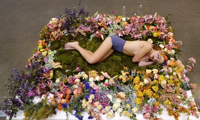 A model lies in a bed of flowers in performance artist Millie Brown's exhibit at the Los Angeles Art Show at the Convention Center in downtown Los Angeles, California, USA, 28 January 2016. The Los Angeles Art Show with hundreds of exhibitors is one of the largest art shows in the United States. (Photo by Mike Nelson/EPA)