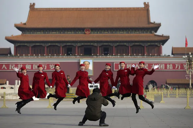 Chinese hostesses, who serve the delegates of the National People's Congress, jump as they pose for photographs on Tiananmen Square during a plenary session of the NPC held at the Great Hall of the People in Beijing Thursday, March 12, 2015. Thousands of delegates from across the country are in the Chinese capital to attend the annual National People's Congress and the Chinese People's Political Consultative Conference. (Photo by Andy Wong/AP Photo)