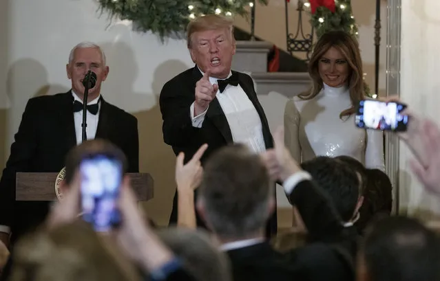 President Donald Trump, joined by Vice President Mike Pence, left, and first lady Melania Trump, right, acknowledges the crowd during the Congressional Ball in the Grand Foyer of the White House in Washington, Saturday, December 15, 2018. (Photo by Carolyn Kaster/AP Photo)