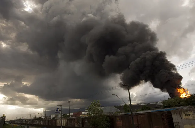 Smoke rises from a fire at a liquid bulk storage facility near Brazil's port of Santos, Thursday, April 2, 2015. The fire broke out Thursday morning at the facility owned by Ultracargo, one of Brazil's largest liquid bulk storage companies. Fuels, chemicals, vegetable oils, ethanol and corrosive products are stored at the site. The Santos fire department said there are no fatalities and that two workers were treated for smoke inhalation. (Photo by Andre Penner/AP Photo)