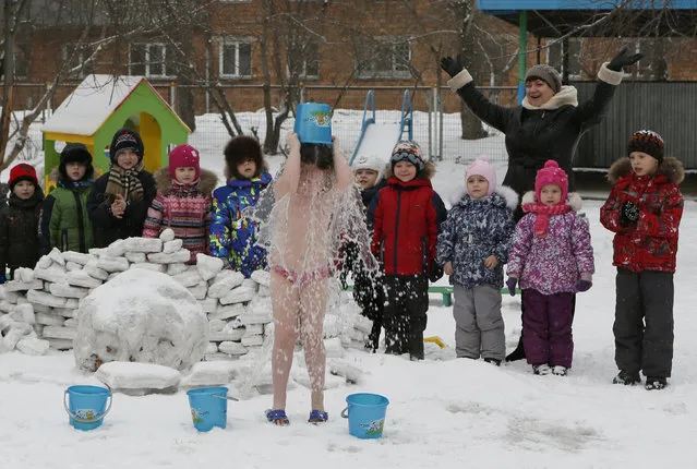 Children watch their classmate pour cold water on herself, under the watch of fitness coach Oksana Kabotko (not pictured), as part of a health and fitness program at a local kindergarten in subzero temperatures, in Krasnoyarsk, Siberia, Russia, February 9, 2016. (Photo by Ilya Naymushin/Reuters)