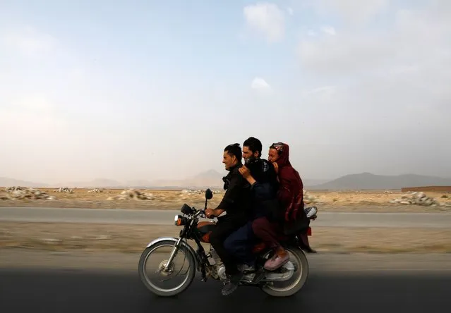 Afghan men ride a motorcycle on the outskirts of Kabul, Afghanistan on July 13, 2021. (Photo by Mohammad Ismail/Reuters)