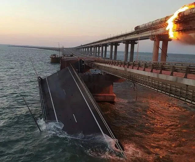 This handout picture released by Security Service of Ukraine shows a fire sparked by a car bomb that has broken out on a key bridge linking Crimea to Russia, near Kerch, on October 8, 2022. The road-and-rail bridge, built on the orders of Russian President Vladimir Putin and inaugurated in 2018, was a key transport link for carrying military equipment to Russian soldiers fighting in Ukraine, especially in the south, as well as ferrying troops across. (Photo by Security Service of Ukraine/AFP Photo)