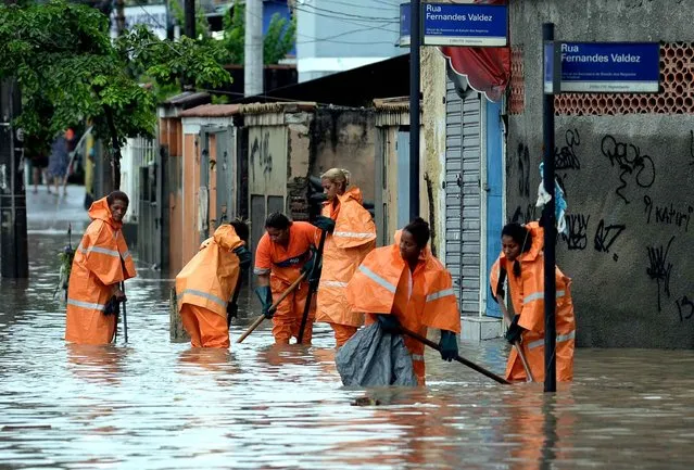 City hall employees work in a flooded street of a suburb in Rio de Janeiro on December 11, 2013. Alert was declared in Rio de Janeiro due to torrential rains falling since early morning. Fire officials reported one missing person and two partially buried by landslides. (Photo by Vanderlei Almeida/AFP Photo)