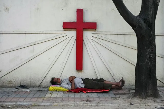 A man sleeps at a pavement outside a church in Secunderabad, the twin city of Hyderabad on December 8, 2023. (Photo by Noah Seelam/AFP Photo)