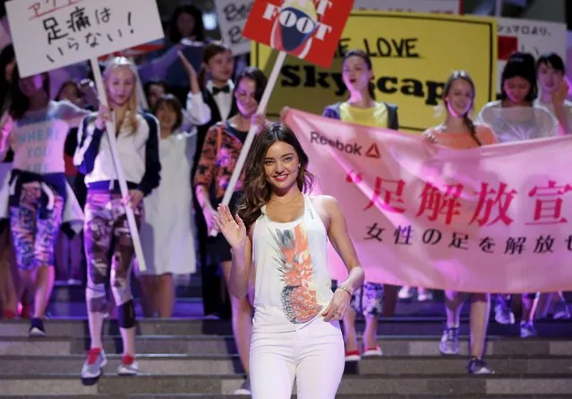 Australian model Miranda Kerr (C) leads women holding placards and a banner (R), which reads “Women be freed from bad-fitting shoes”, during a promotional event for the Reebok Skyscape shoes series at the Omotesando Hills in Tokyo April 15, 2015. (Photo by Issei Kato/Reuters)