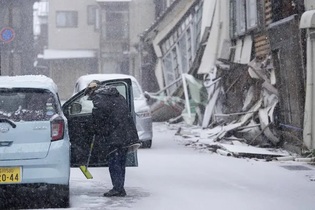 A person cleans his car from snow in Wajima in the Noto peninsula facing the Sea of Japan, northwest of Tokyo, Sunday, January 7, 2024. Monday's temblor decimated houses, twisted and scarred roads and scattered boats like toys in the waters, and prompted tsunami warnings. (Photo by Hiro Komae/AP Photo)
