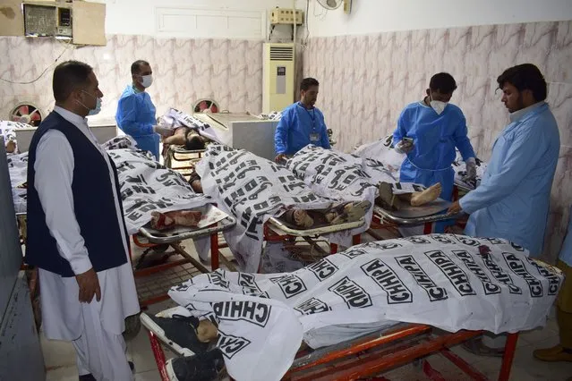 Pakistani paramedical personnel stand next to the covered bodies of suspect militants who were killed by security forces, at a morgue in Quetta, Pakistan, August 31, 2021. Pakistan's counter-terrorism units raided a hideout of the Islamic State group in the restive southwestern Baluchistan province before dawn on Tuesday, setting off a shootout that killed some 11 militants, the police said. (Photo by Arshad Butt/AP Photo)