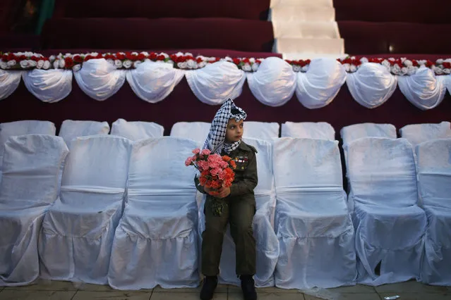 A Palestinian girl dressed in a military uniform and traditional kufiya (headscarf) attends a mass wedding for 50 couples funded by the office of Palestinian President Mahmoud Abbas, in Gaza City February 4, 2014. (Photo by Suhaib Salem/Reuters)
