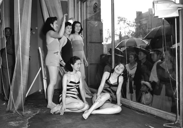 To draw the public's attention to a new line of bathing suits, a Tokyo department store used live models to show off the suits on June 5, 1950. The rain didn't bother the curious, and both the girls and the crowd seemed to like the idea of staring at each other through the glass. (Photo by AP Photo via The Atlantic)