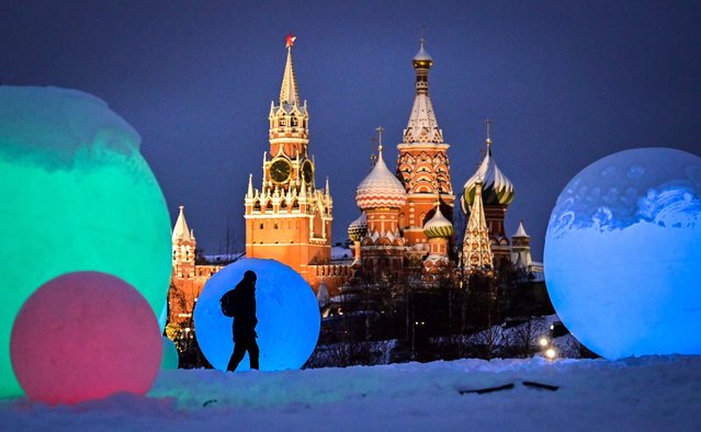 A pedestrian walks past a Chrsimas and New Year's decorations at Zaryadie park, in front of the Spasskaya tower of the Kremlin and the Saint Basil cathedral, in central Moscow, on December 15, 2021. (Photo by Yuri Kadobnov/AFP Photo)