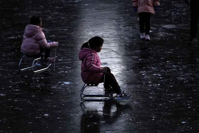 Children play ice skating on a frozen river near a residential area during the New Year holiday in Beijing, Monday, January 3, 2022. (Photo by Andy Wong/AP Photo)