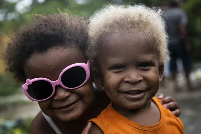Children smile for the camera during a Christmas food donation by “Covid Sem Fome” or Covid Without Hunger, a non-governmental organization that works to releave hunger in the Jardim Gramacho favela of Rio de Janeiro, Brazil, Sunday, December 19, 2021. (Photo by Bruna Prado/AP Photo)