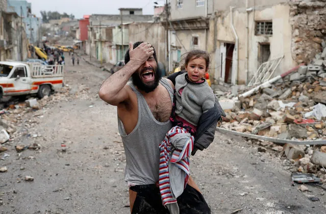 A man cries while he carries his daughter as he walks from Islamic State controlled part of Mosul towards Iraqi special forces soldiers during a battle in Mosul, Iraq, March 4, 2017. (Photo by Goran Tomasevic/Reuters)